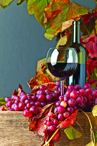 Red wine and grape with vine leaves on a old wooden table.Copy space.