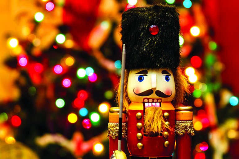 soldier nutcracker statue standing in front of decorated christmas tree