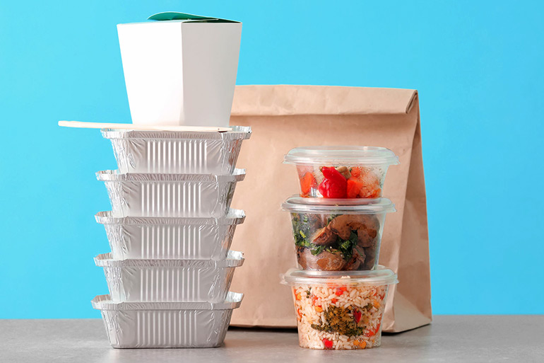 Food in various takeout containers on blue background