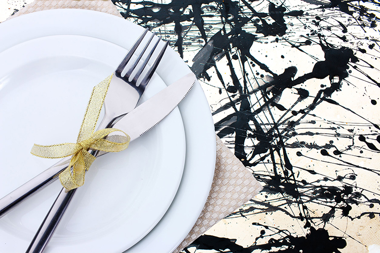 white empty plates with fork and knife tied with a ribbon on a grey tablecloth