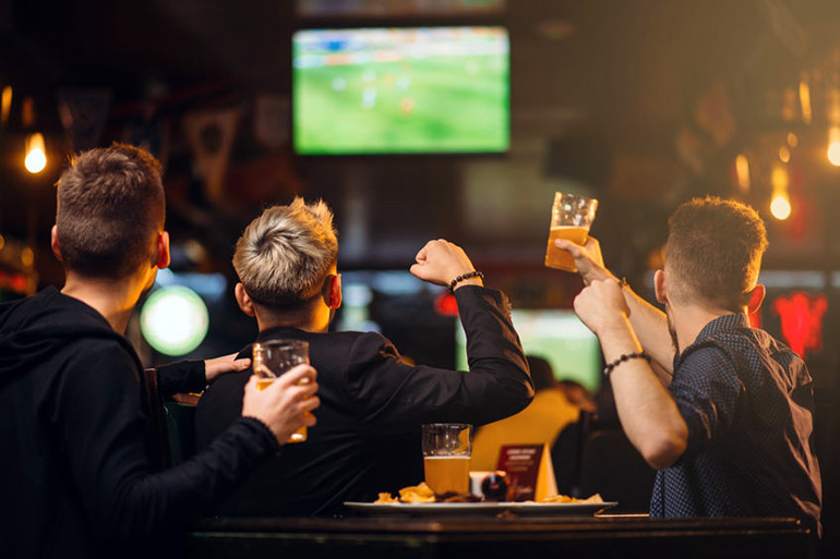 Fans cheering in a sports bar watching Super Bowl LIII