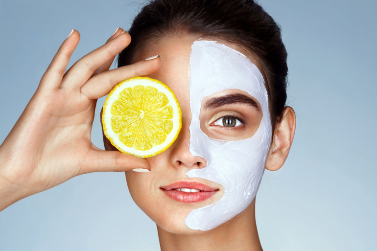 Lovely girl holding a slice of lemon in front of her face and smiling. Photo of girl receiving spa treatments. Beauty & Skin care concept