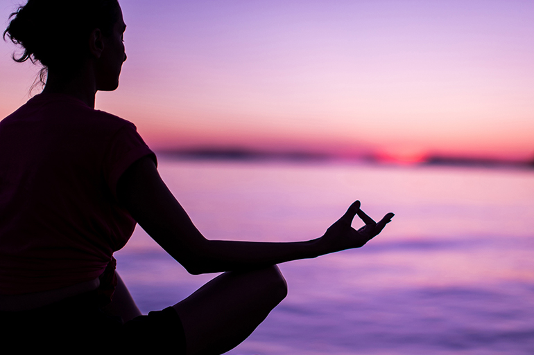 Calm Mindful Woman Meditating On Beach Faced Towards Majestic Sunset