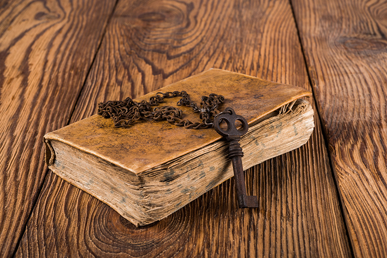 Old key with chain on an book