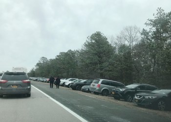 Police officers walk past all the cars parked for funeral of fallen NYPD Detective Brian Simonsen on Montauk Highway in Hampton Bays