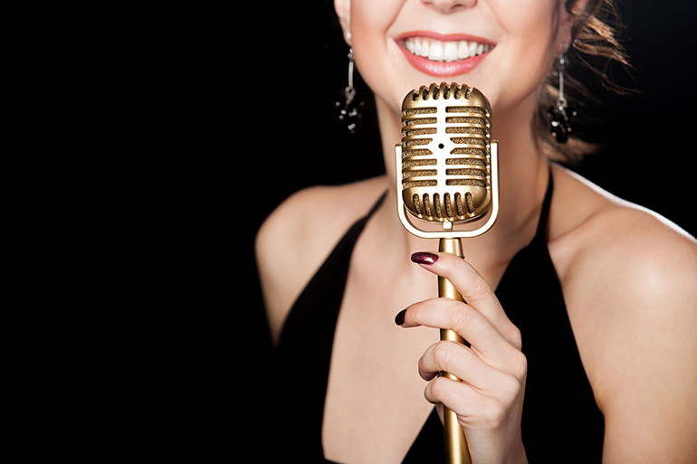 Beautiful girl vocalist with smile holding golden vintage microp