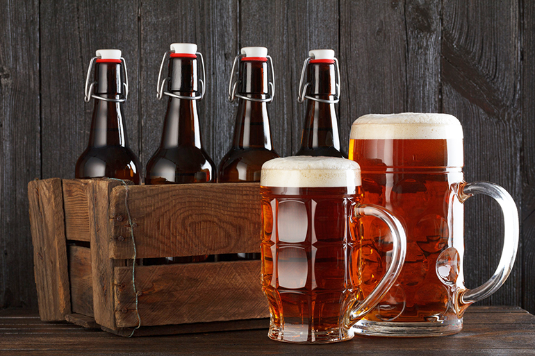 Beer glass with vintage wooden box full of beeer bottles on wooden table still life