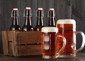 Beer glass with vintage wooden box full of beeer bottles on wooden table still life