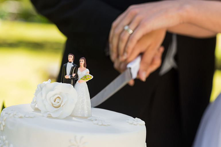 Extreme close-up mid section of a newlywed cutting wedding cake