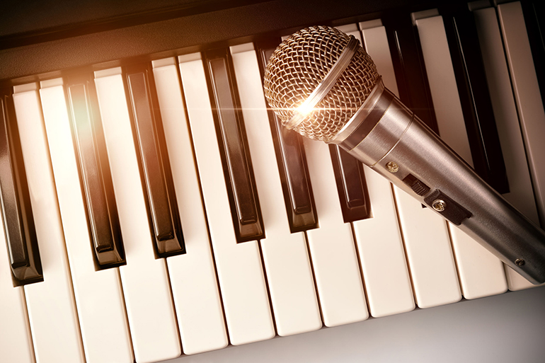 Piano and microphone with golden sparkles. Horizontal Composition.Top view
