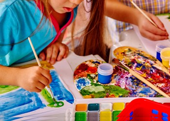 Close up of girl with brush painting in kindergarten .