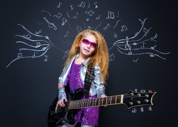 Little rock star singing with her electric guitar over musical background. Music concept.