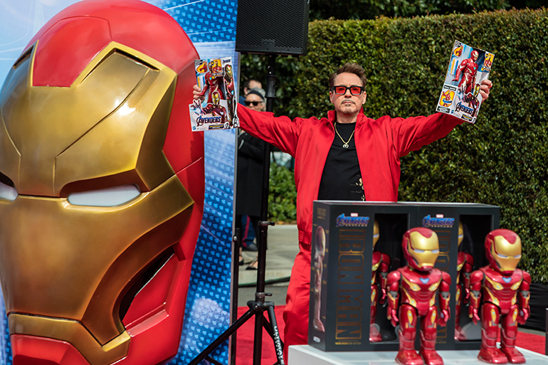 Robert Downey Jr. holds up toys at the Avengers Universe Unites event