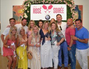 Friends gather in front of the Rosé Soirée step and repeat