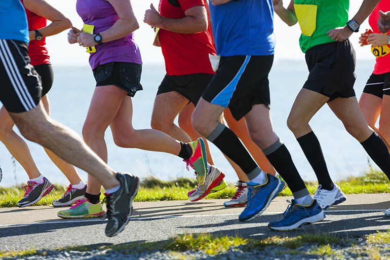 Group of runners compete in the race on coastal road