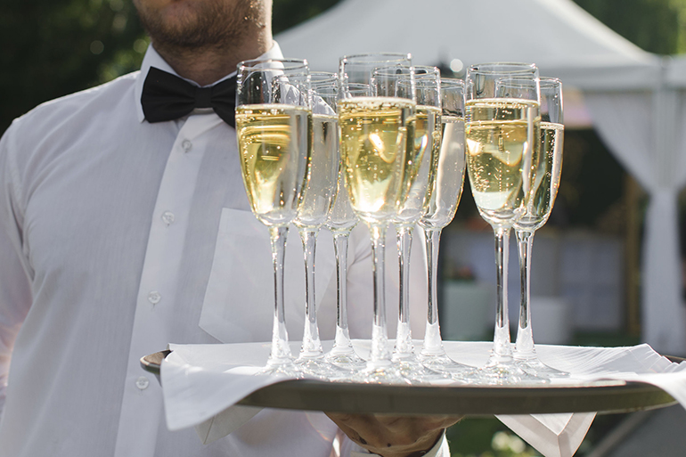 Waiter serving champagne on a tray outdoors