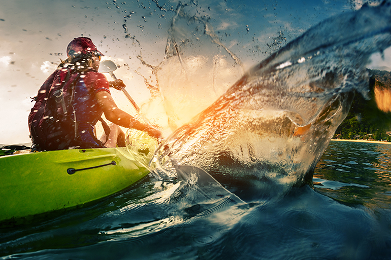 Young lady paddling hard the kayak with lots of splashes