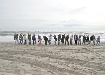 Dan's Papers staff holding the Great Ecuadorian Eel on the beach