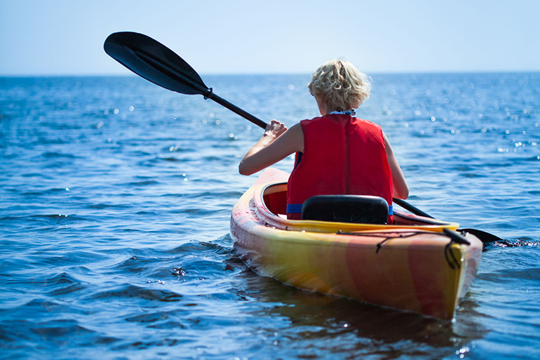 Young Woman Wearing a Safety Vest Heading out to sea Alone on Calm Water