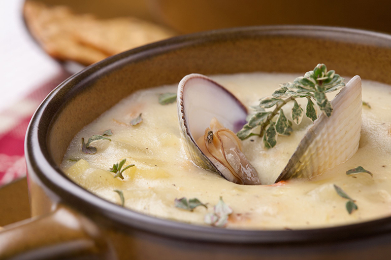 bowls of hot delicious clam chowder garnished with fresh thyme, and multy grain crackers