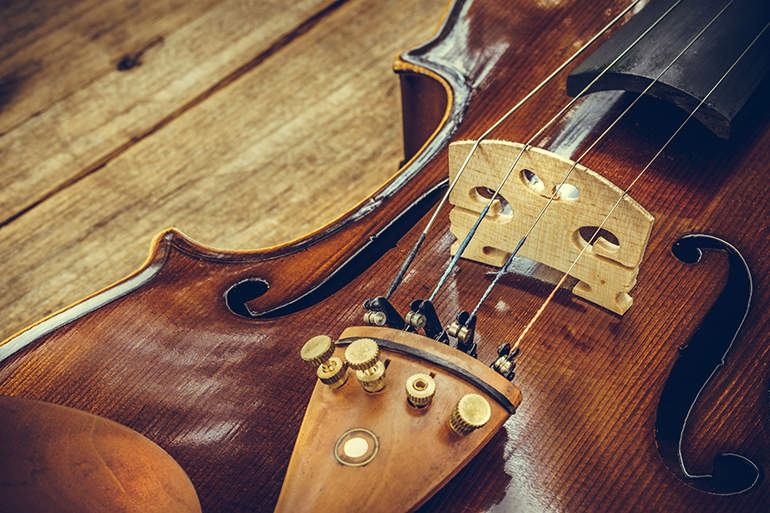 Art. Closeup of old wooden violin stringed instrument on old wooden table. Classical music.
