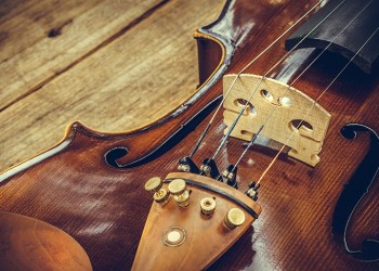 Art. Closeup of old wooden violin stringed instrument on old wooden table. Classical music.