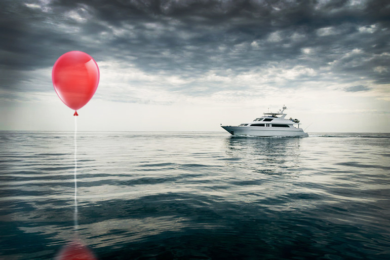 Red balloon at sea with boat
