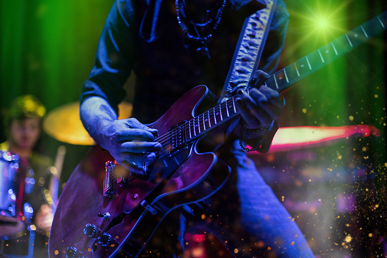 Guitarist playing on electric guitar. Rock concert stage.