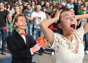 Man proposing to woman who is screaming in terror at flash mob behind them