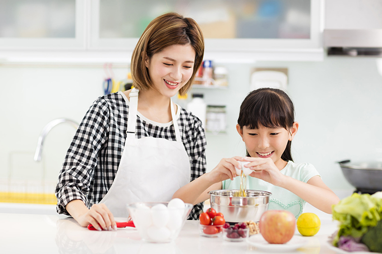 Happy mother and child in kitchen preparing cookies