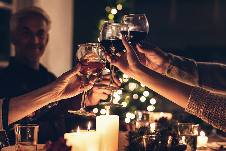 Close up shot of family toasting wine at christmas dinner. Family enjoying christmas dinner together at home, with focus on hands and wine glasses.