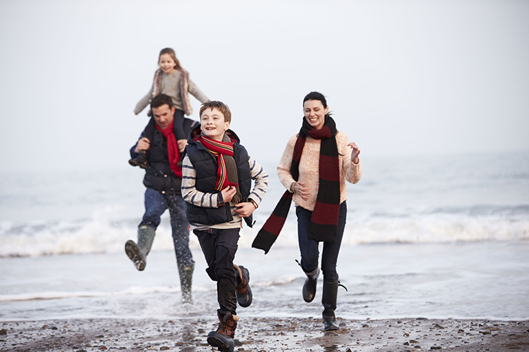 Family Running Along Winter Beach