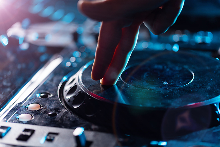 DJ turntable console mixer controlling with two woman hands