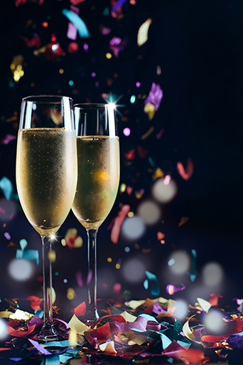 Two bright icy champagne glasses and confetti falling
