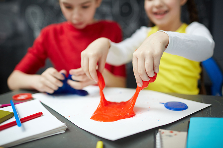 Human hands pulling red slime during play