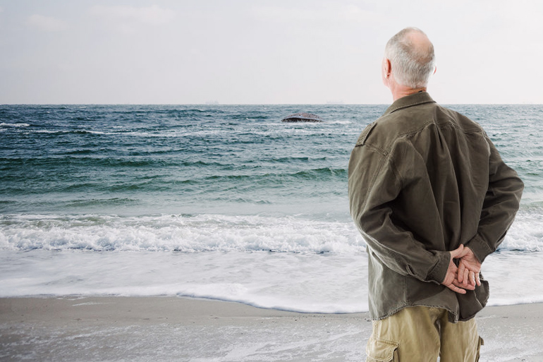 Old Man McGumbus watches his bunker floating out to sea from beach