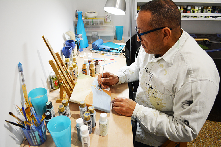 Michael A. Butler focusing on a painting her started some time ago