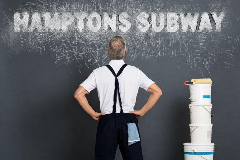 Rear view of painter looking at grey wall to paint. Mature workman with paint bucket and roller looking up at expressively painted Hamptons Subway sign