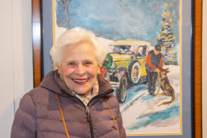 Priscilla Bruno posing with a painting she's featured in by son-in-law Mickey Paraskevas