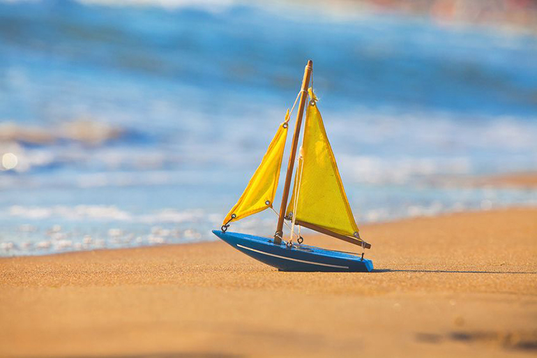 Little toy sailboat on sandy beach