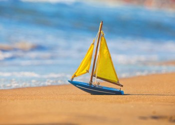 Little toy sailboat on sandy beach