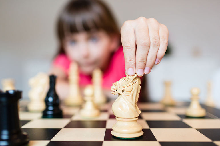 Young white child playing a game of chess on large chess board.