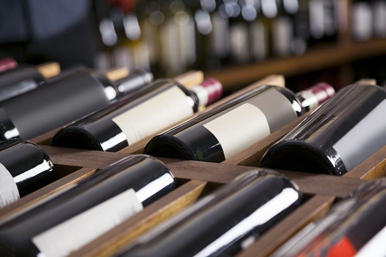 Red wine bottles displayed on shelves in supermarket