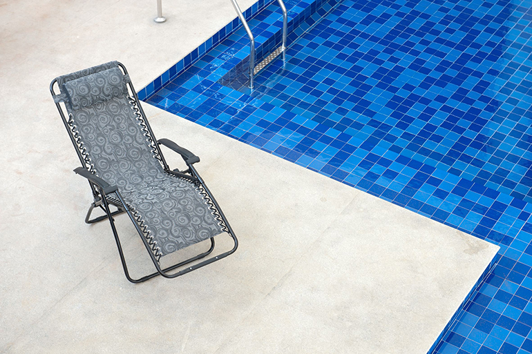 reclining chair along a swimming pool