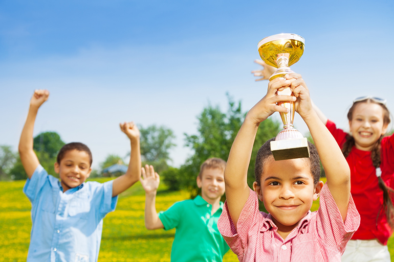 Brendan Hickcock shows off his airport noise idea trophy in front of group of kids