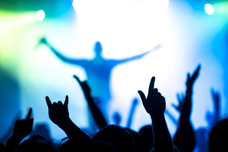 silhouettes of concert crowd in front of bright stage lights