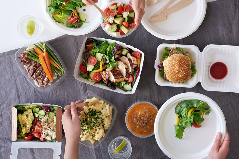 Convenient takeaway takeout food for party, overhead spread of assorted food with hands serving up