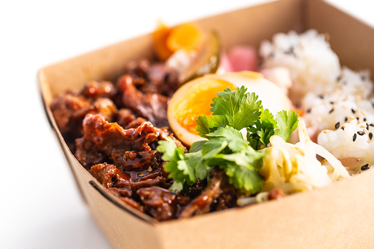 Japanese asian meal in a box of recycled paper isolated on white background. Concept of organic food packaging.
