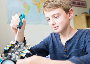Boy Assembling Robotic Kit In Bedroom