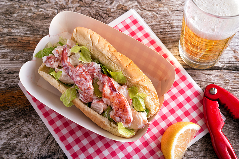 A delicious lobster roll with beer on a rustic wood table